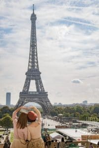 photo of two women posing in front of eiffel tower paris france during day time
